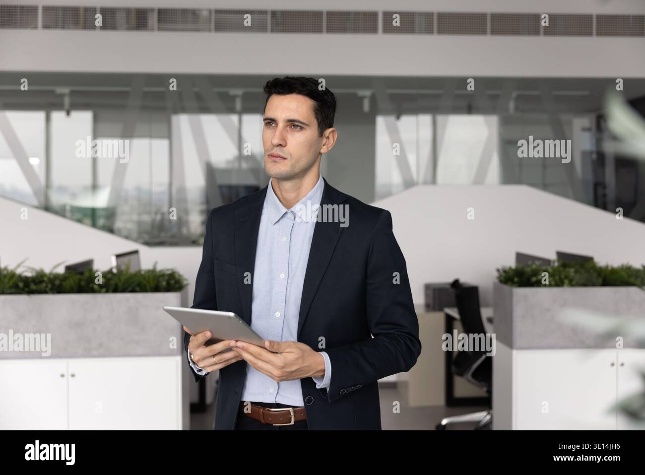 Latin businessman holding tablet thinking about problem solution in office Stock Photo