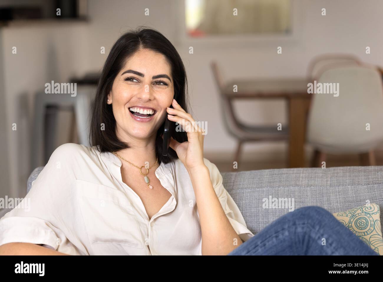 Happy relaxed young Hispanic woman talking on cellphone Stock Photo