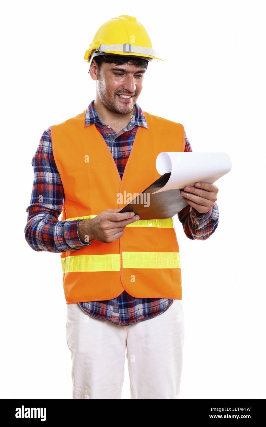 Young happy Persian man construction worker smiling while reading on clipboard Stock Photo