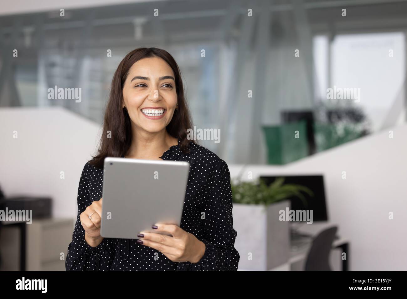 Cheerful Middle Eastern female professional using tablet pc in office Stock Photo