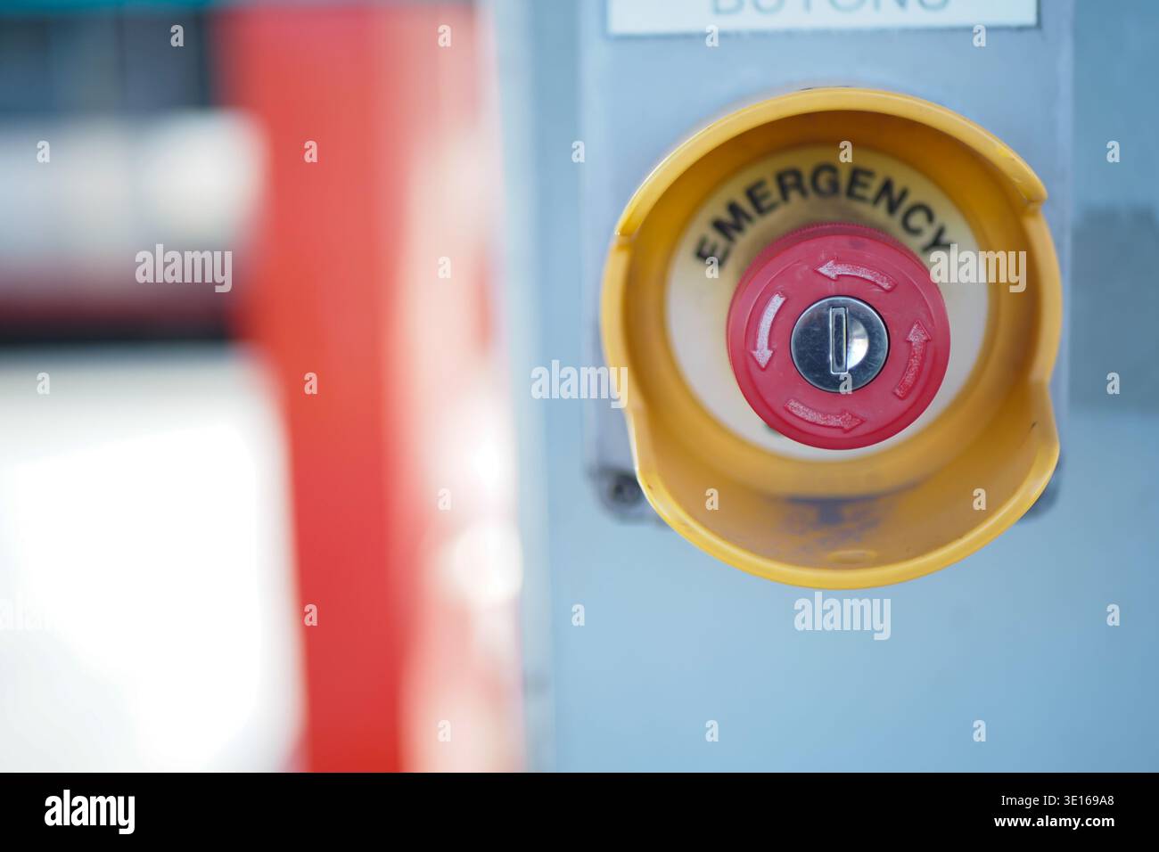 Red emergency button on a gray panel at a facility Stock Photo