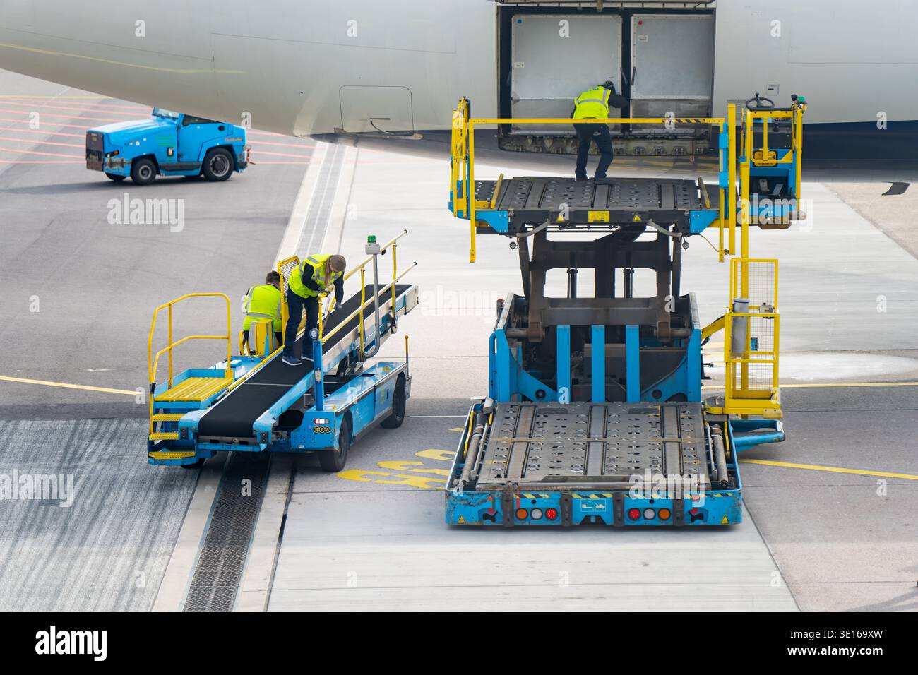 Airside cargo equipment and airport workers positioned under a ...