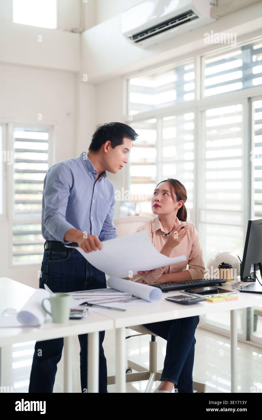 Professional Asian team collaboration reviewing architectural blueprints design solutions Engineers discussing project development in bright office en Stock Photo