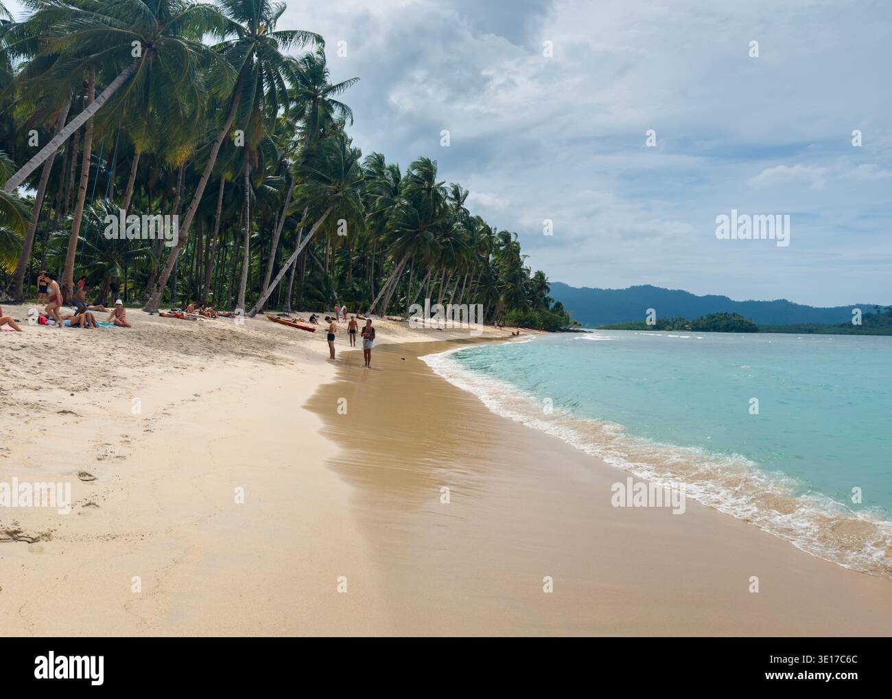 Tourists relaxing and walking along White Beach in Port Barton, Palawan, Philippines, with palm-lined shore, turquoise sea, and tropical scenery. - Smartphone Captured Stock Image
