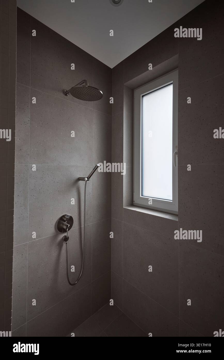 Dark tiled shower room with small window. Stock Photo
