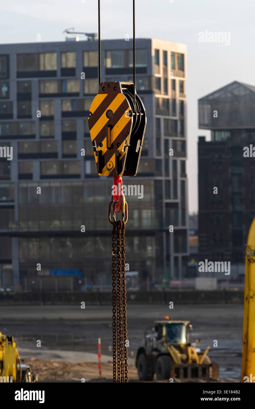 Close up of yellow (industrial) heavy-duty crane hook block, single sheave (pulley) model for heavy lifting operations on construction site with build Stock Photo