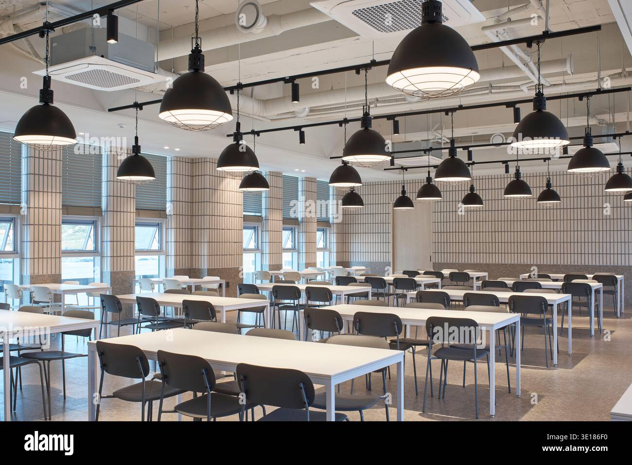 Large dining hall with pendant lights and communal seating Stock Photo ...