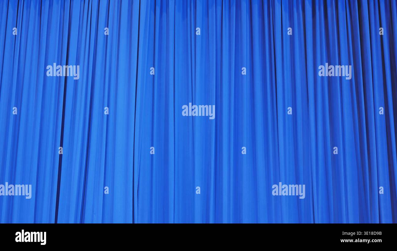 Blue theater curtain with vertical folds creating a dynamic texture backdrop Stock Photo