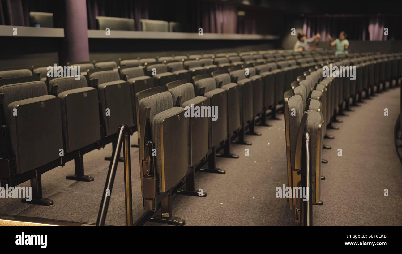 Empty seats in curved rows inside a dark modern theater auditorium Stock Photo
