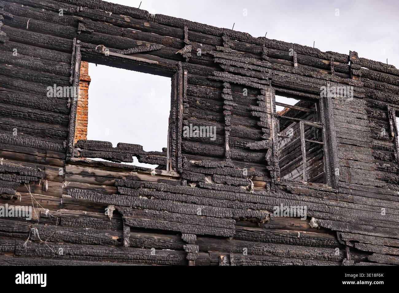 Burnt house wall with charred wood texture and empty window frames ...