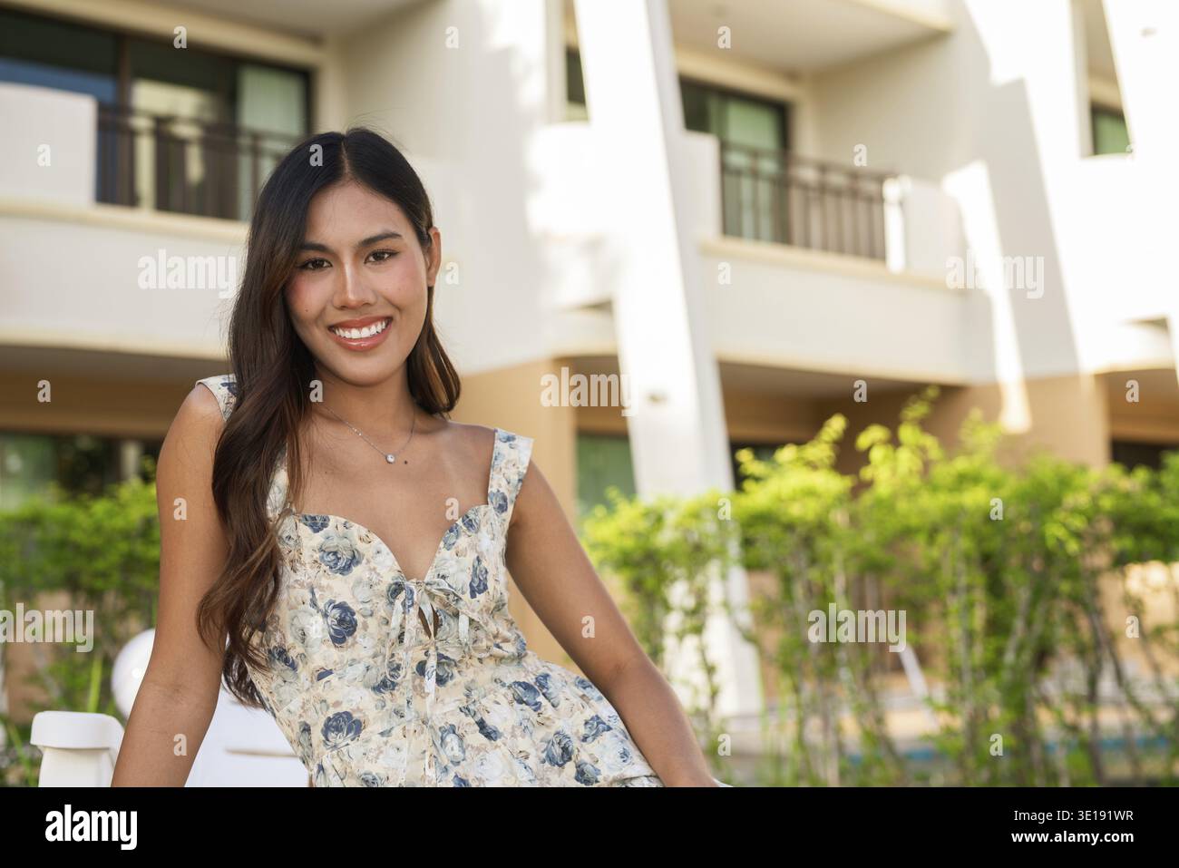 Young happy woman sitting outdoors during summer Stock Photo