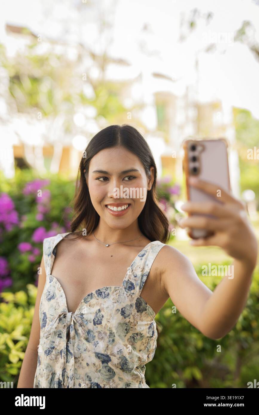 Young Asian woman using phone outdoors Stock Photo