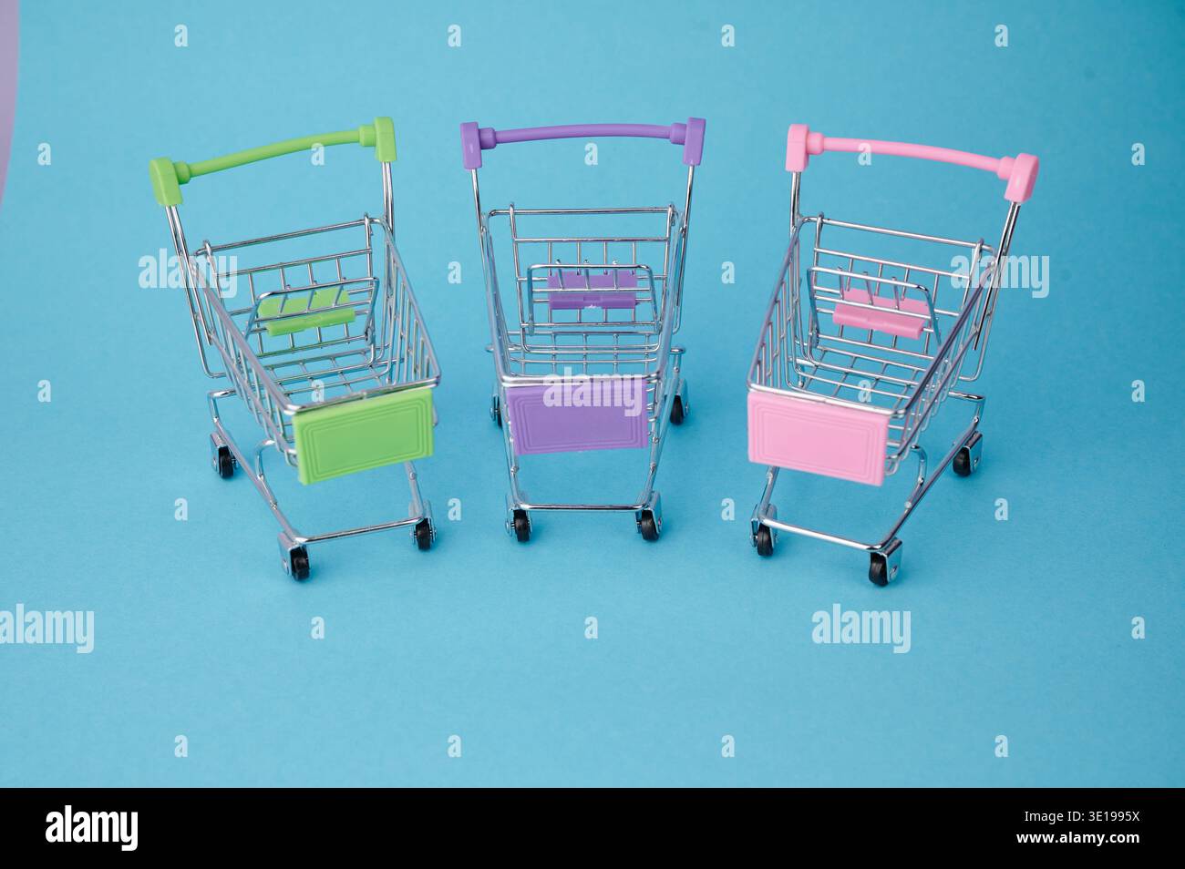 Three small shopping carts sit on a blue background. Stock Photo