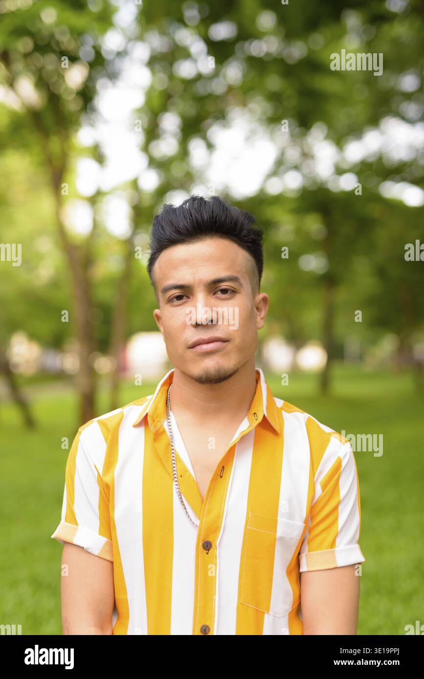 Portrait of young handsome multi ethnic man relaxing at the park outdoors Stock Photo