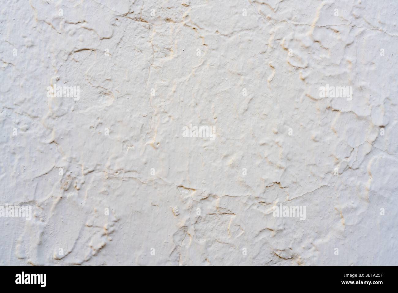 Weathered white plaster wall surface showing uneven texture and fine cracks. Stock Photo