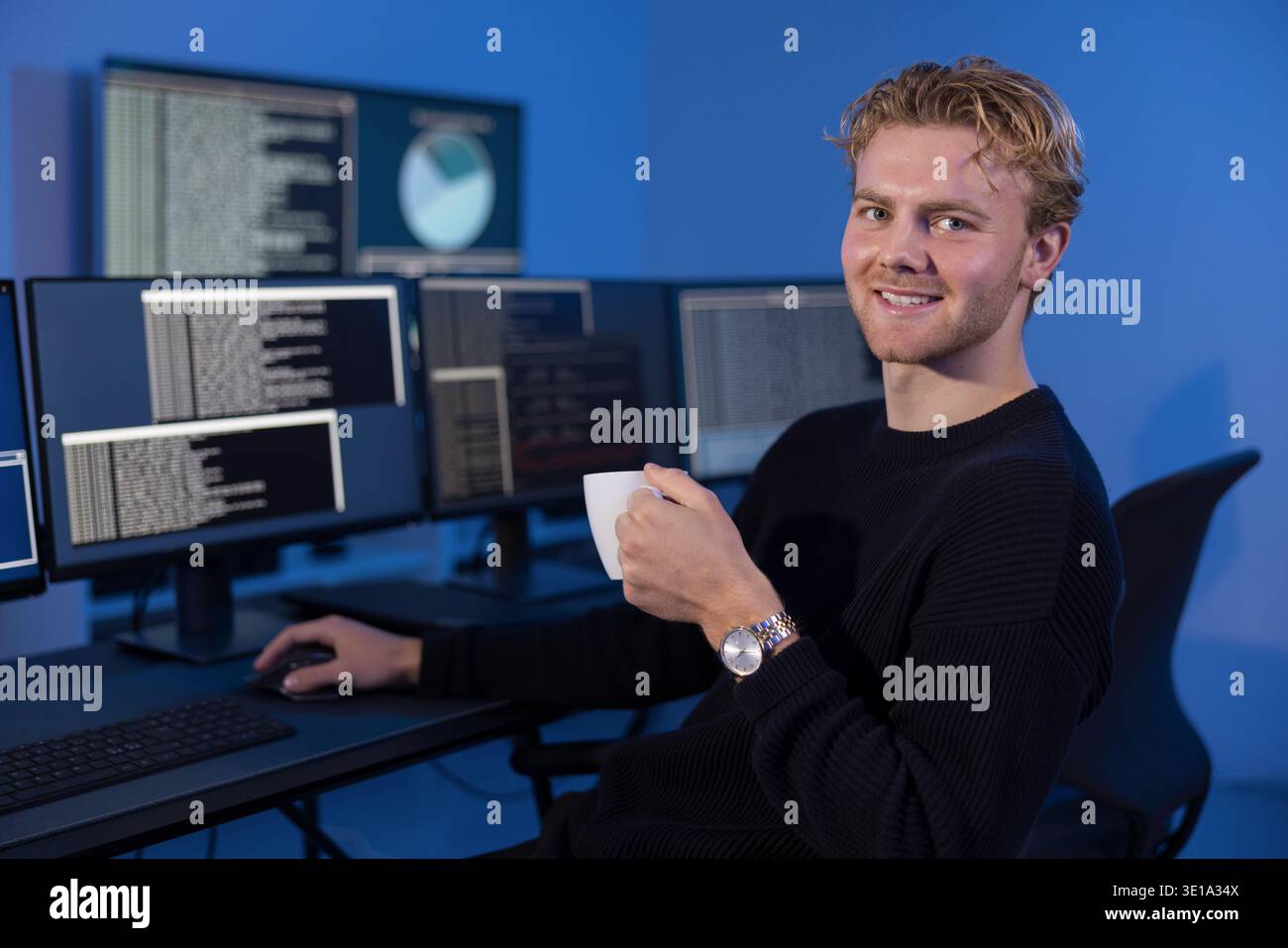 Young IT professional monitors system logs in SOC control room Stock Photo