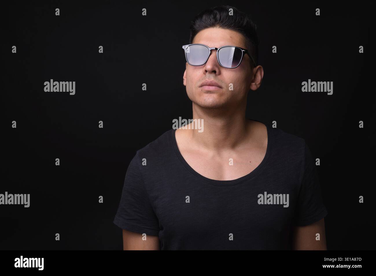 Studio shot of young handsome multi ethnic man against black background Stock Photo