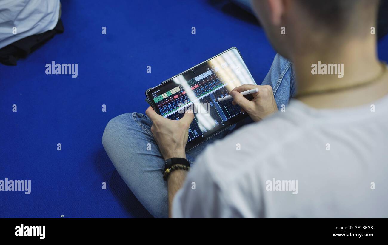 Person mixing audio on a tablet using a stylus, doing sound engineering remotely Stock Photo