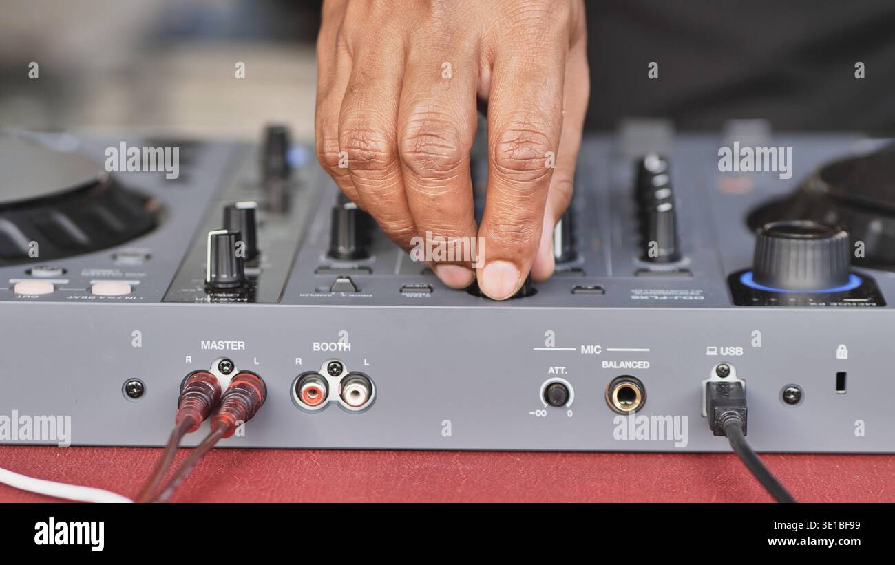 Hand adjusting knobs and faders on a DJ controller, creating music for a festive event Stock Photo