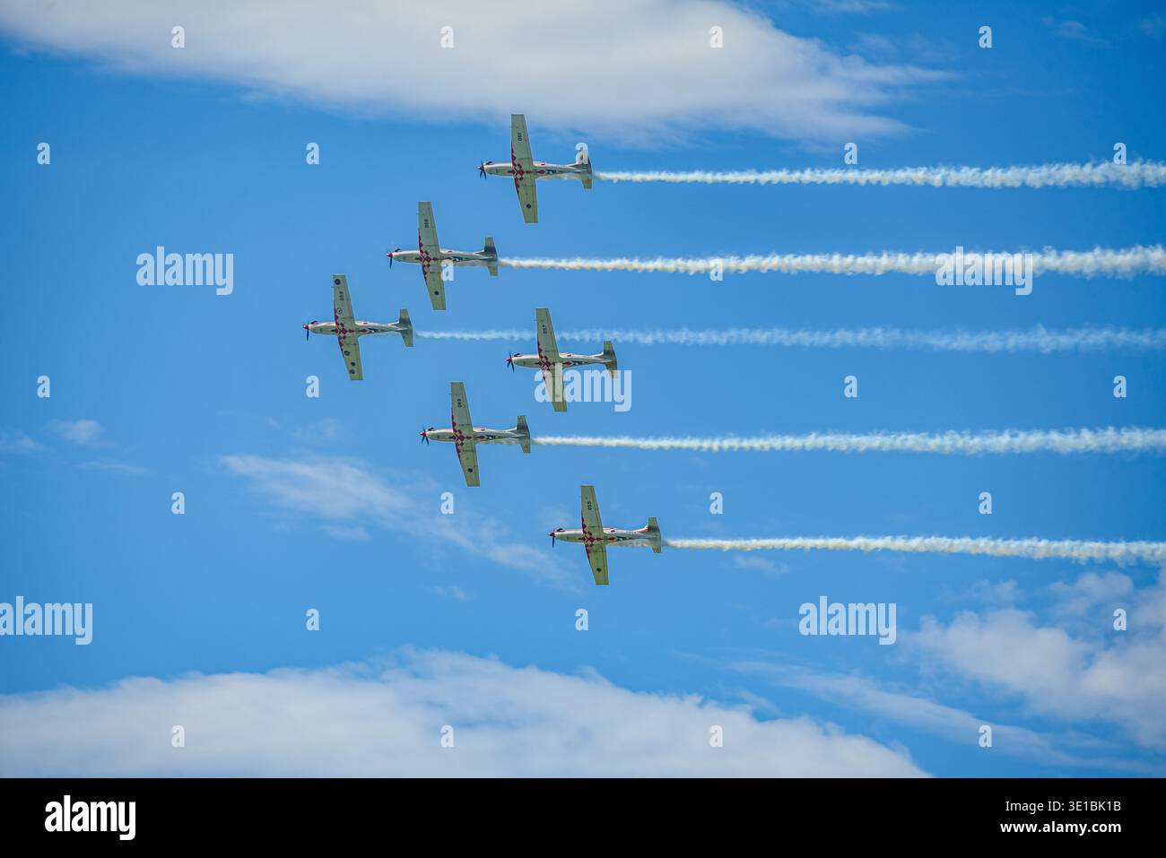 A group of aerobatic jet aircraft flying in perfect formation during an airshow, leaving smoke trails against a clear blue sky during Nato days in Cze Stock Photo