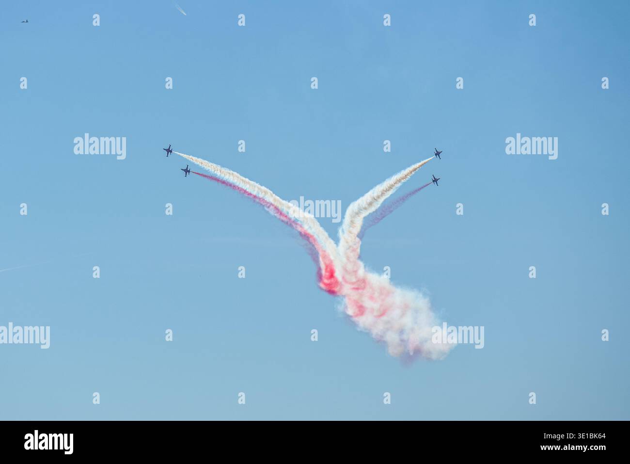 A group of aerobatic jet aircraft flying in perfect formation during an airshow, leaving smoke trails against a clear blue sky during Nato days in Cze Stock Photo