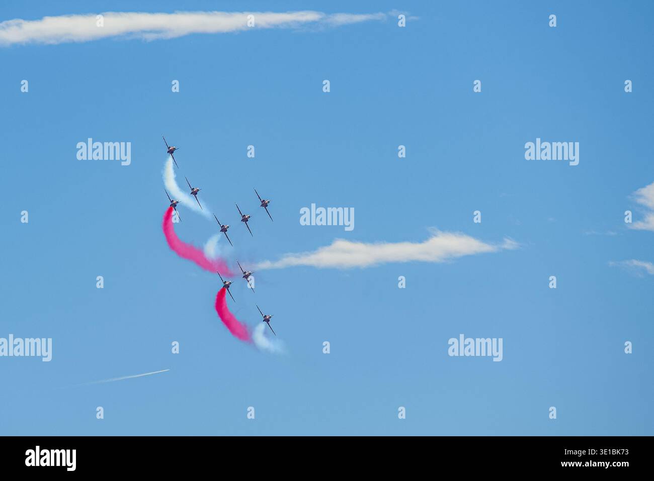 A group of aerobatic jet aircraft flying in perfect formation during an airshow, leaving smoke trails against a clear blue sky during Nato days in Cze Stock Photo