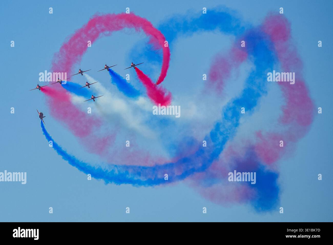 A group of aerobatic jet aircraft flying in perfect formation during an airshow, leaving smoke trails against a clear blue sky during Nato days in Cze Stock Photo