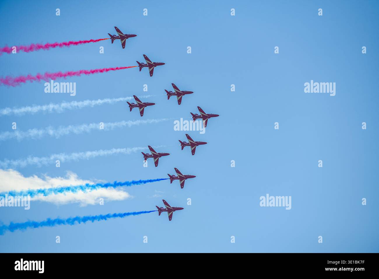 A group of aerobatic jet aircraft flying in perfect formation during an airshow, leaving smoke trails against a clear blue sky during Nato days in Cze Stock Photo