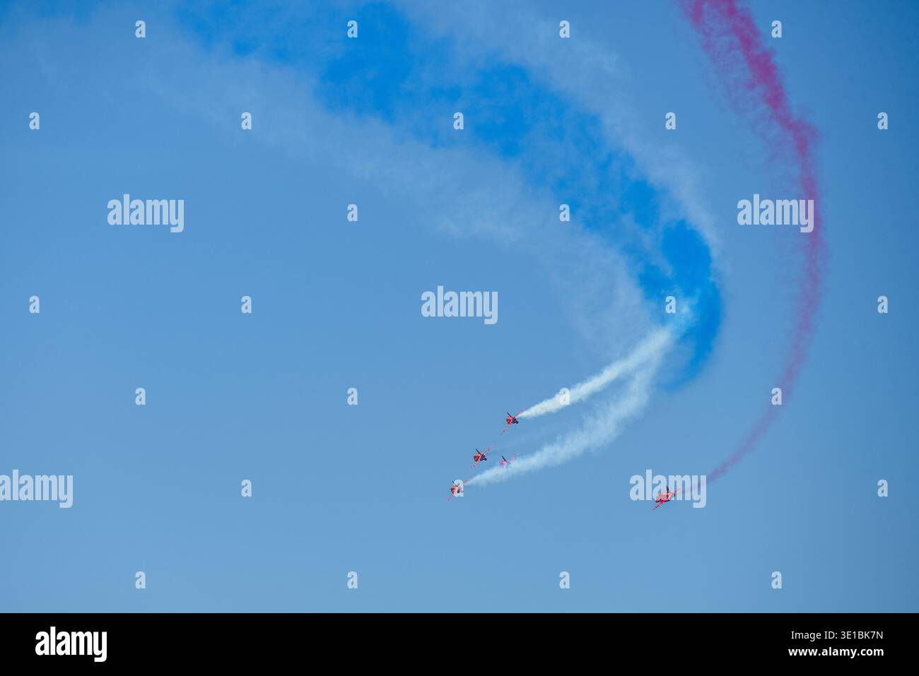 A group of aerobatic jet aircraft flying in perfect formation during an airshow, leaving smoke trails against a clear blue sky during Nato days in Cze Stock Photo