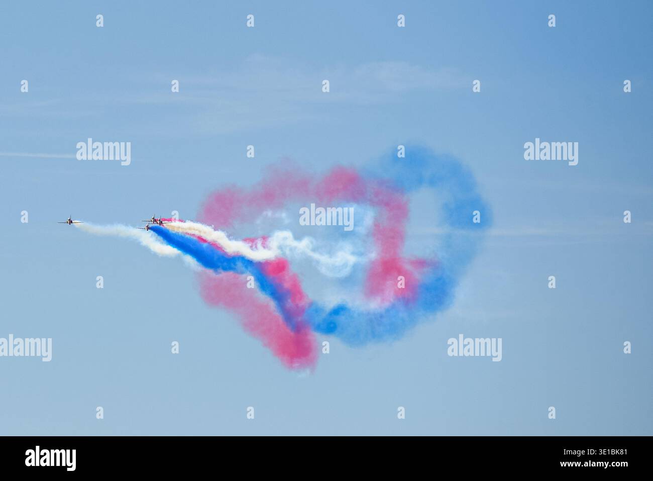 A group of aerobatic jet aircraft flying in perfect formation during an airshow, leaving smoke trails against a clear blue sky during Nato days in Cze Stock Photo