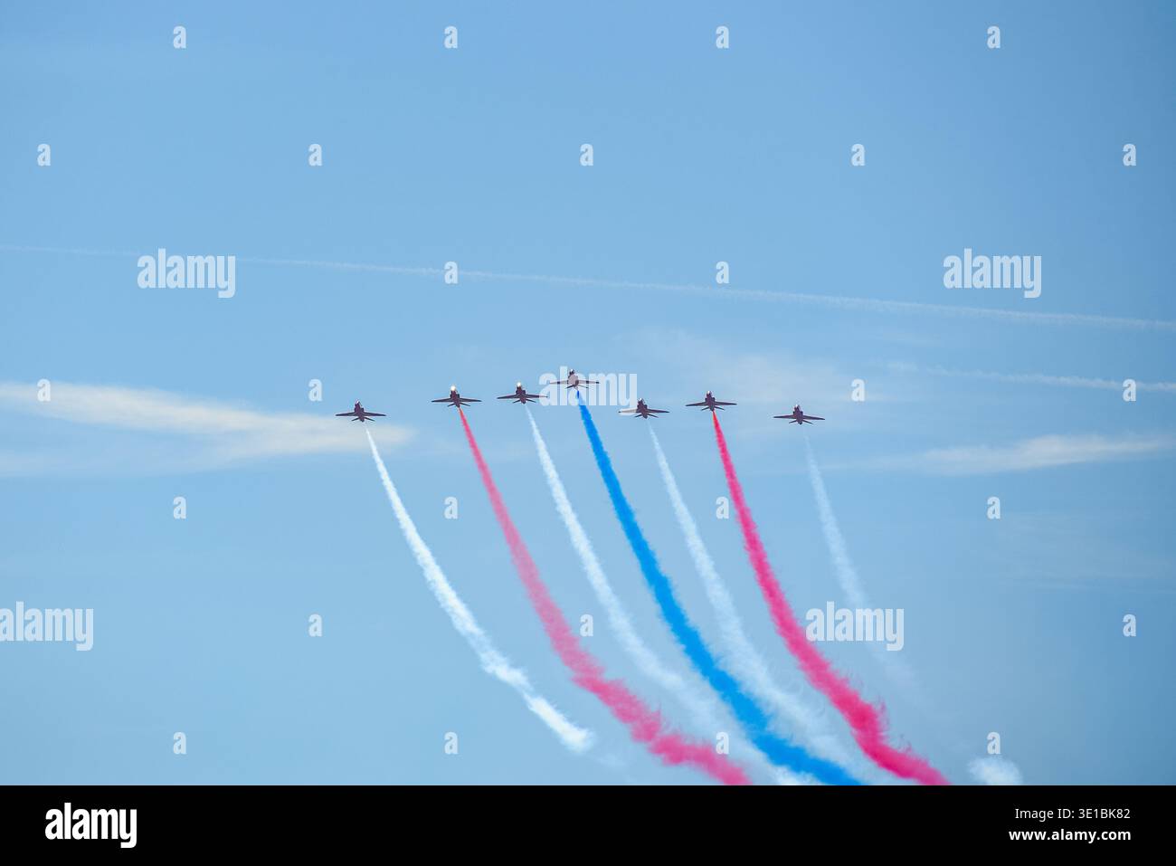 A group of aerobatic jet aircraft flying in perfect formation during an airshow, leaving smoke trails against a clear blue sky during Nato days in Cze Stock Photo