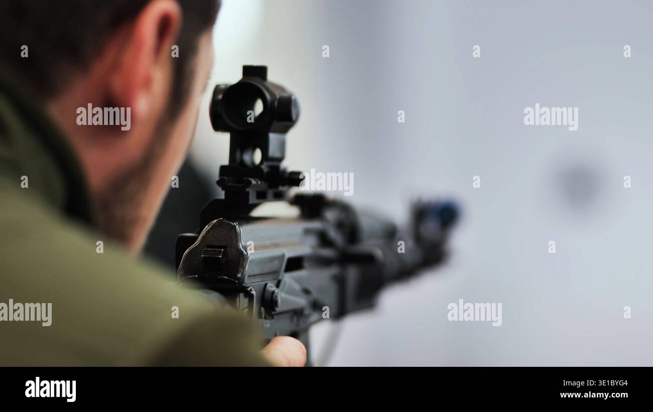 Shooter aiming rifle with optical sight at a target for military ...