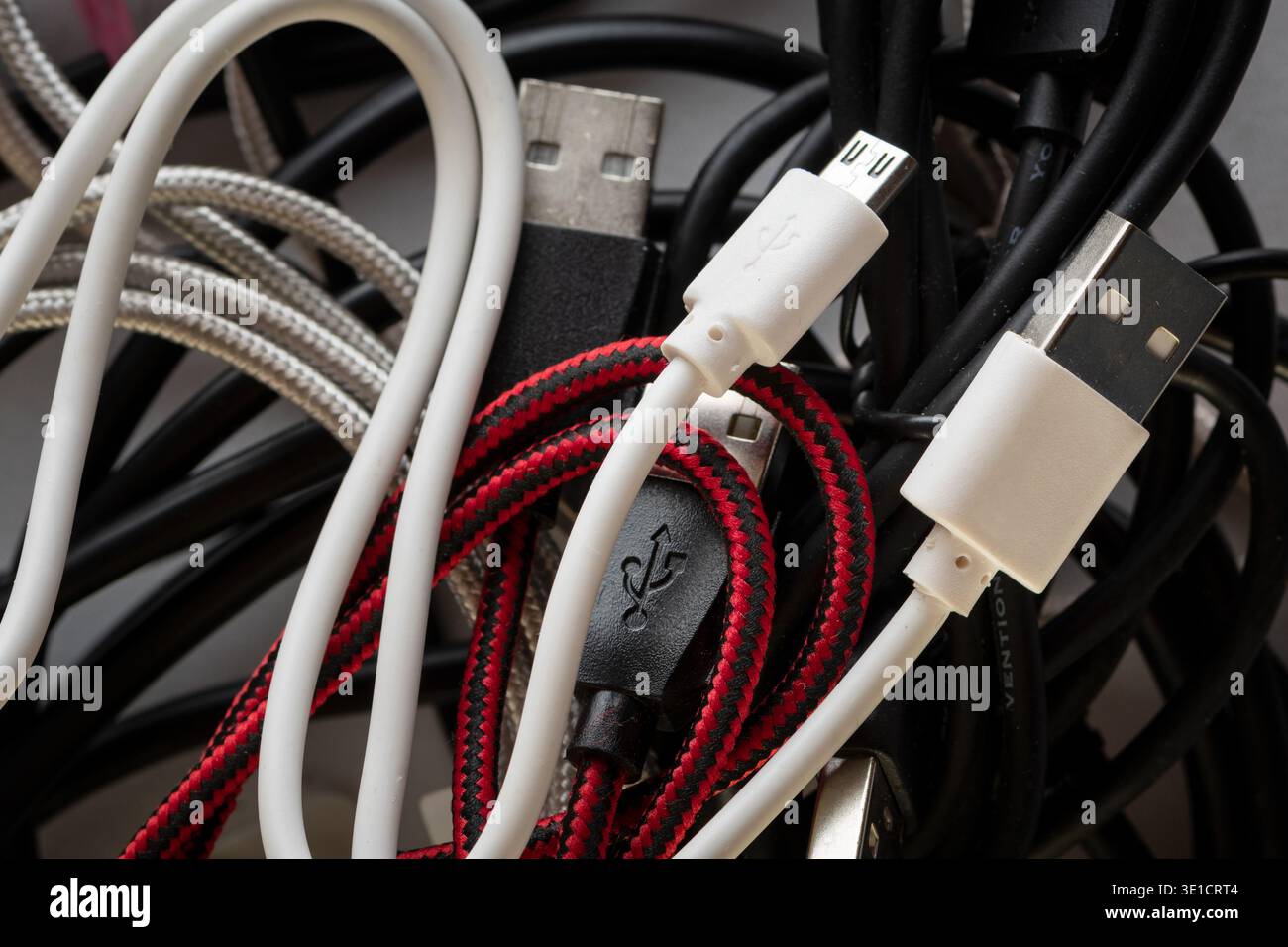 Pile of tangled cables and USB connectors representing digital chaos, stress and disorganized technology environment. Stock Photo