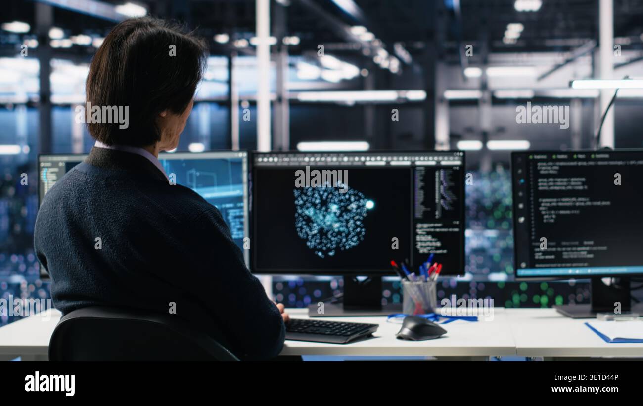 Data center system administrators using machine learning algorithms on PC to analyze datasets. Server farm employees using AI neural networks on devices to recognize data patterns, camera A Stock Photo