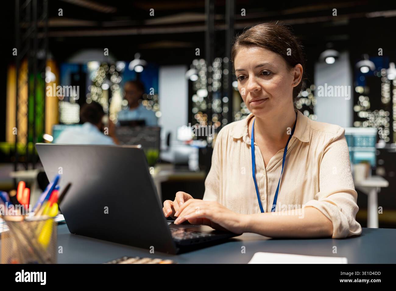 Female employee in office completing spreadsheets on laptop, inputting and analyzing data. Woman typing on notebook keyboard, browsing internet, researching information online, working overnight Stock Photo