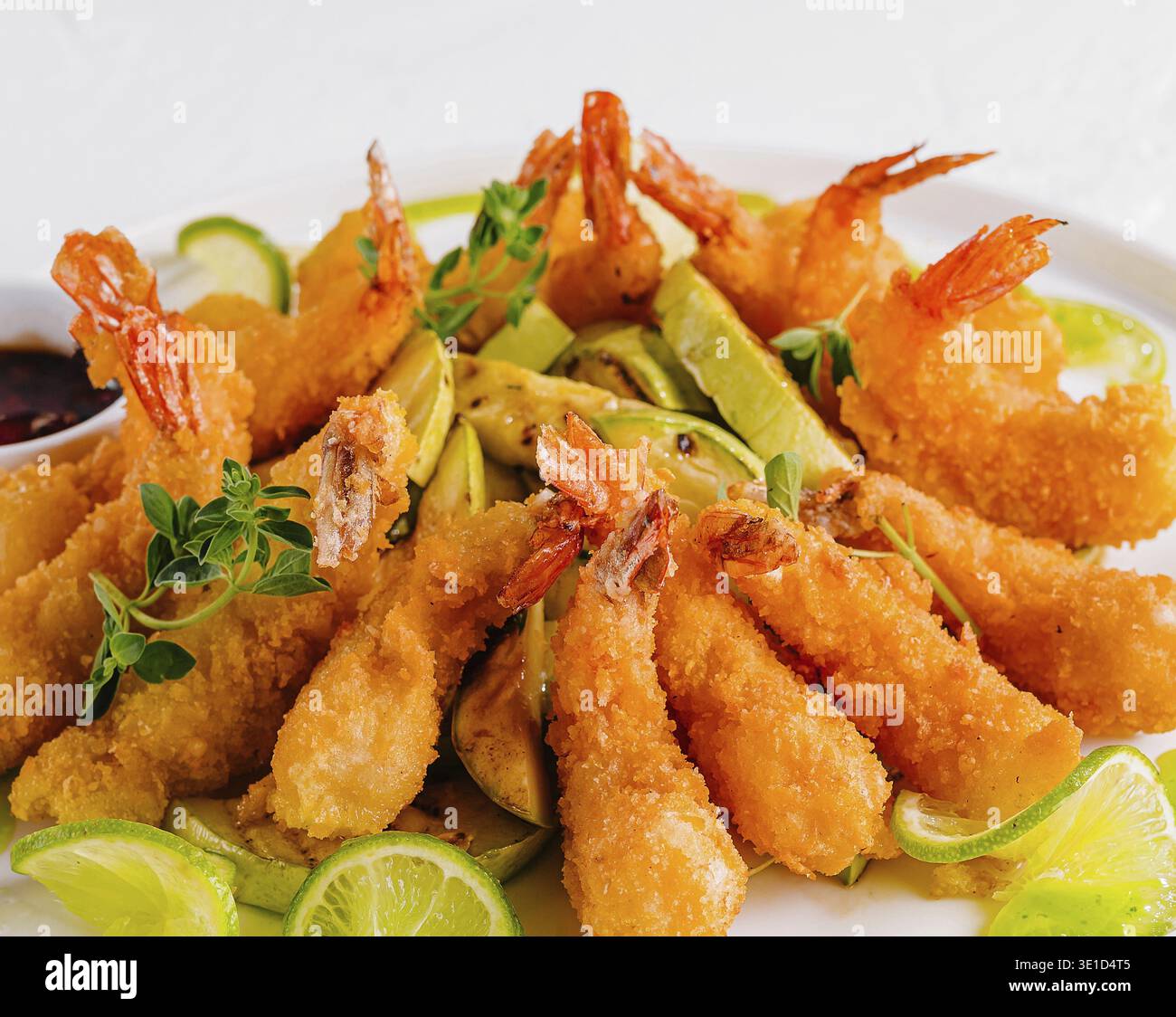 Golden fried shrimp served with slices of fresh lime and dipping sauce, garnished with herbs Stock Photo