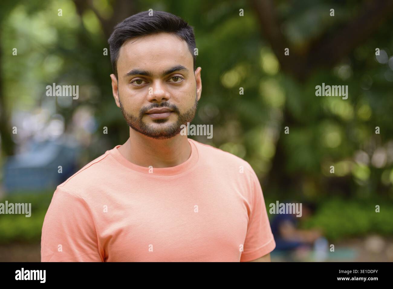 Portrait of young handsome bearded Indian man at the park outdoors Stock Photo