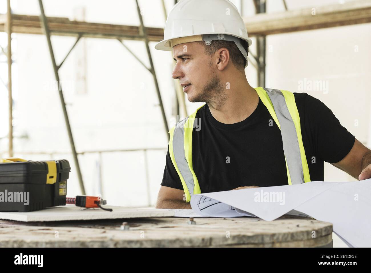 Young is worker checking blueprints during his work on a construction site Stock Photo