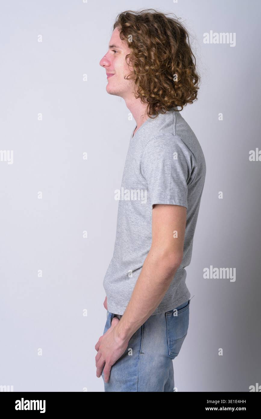 Studio shot of young handsome man with long curly hair against white background Stock Photo