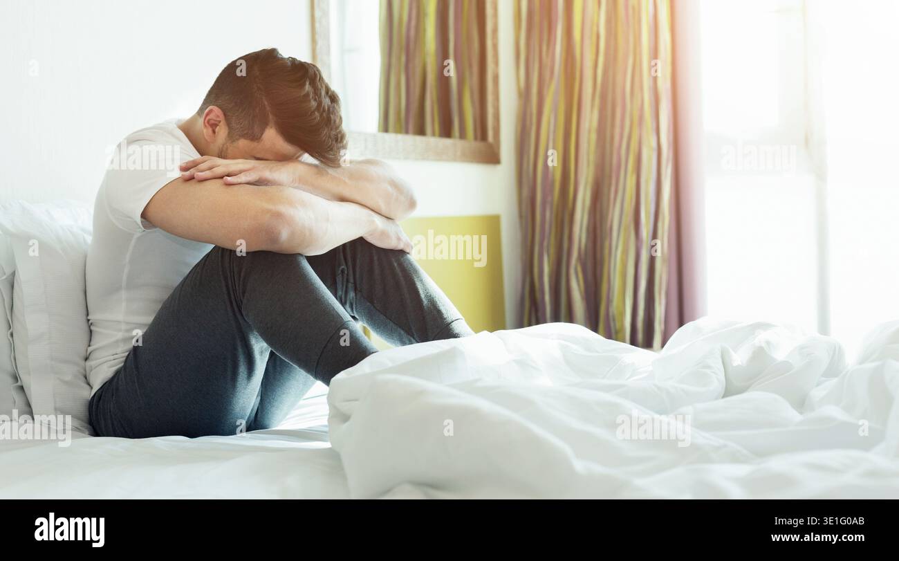 Depressed man sitting on his bed Stock Photo