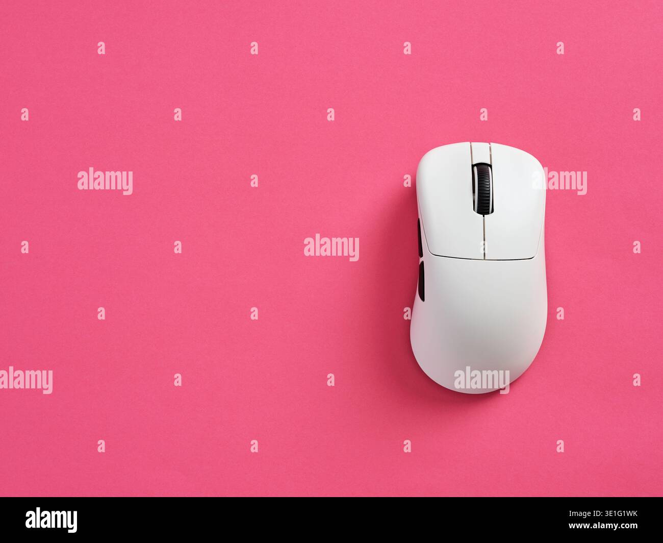 White modern computer mouse resting on a bright pink background, representing technology, computing, and digital work Stock Photo