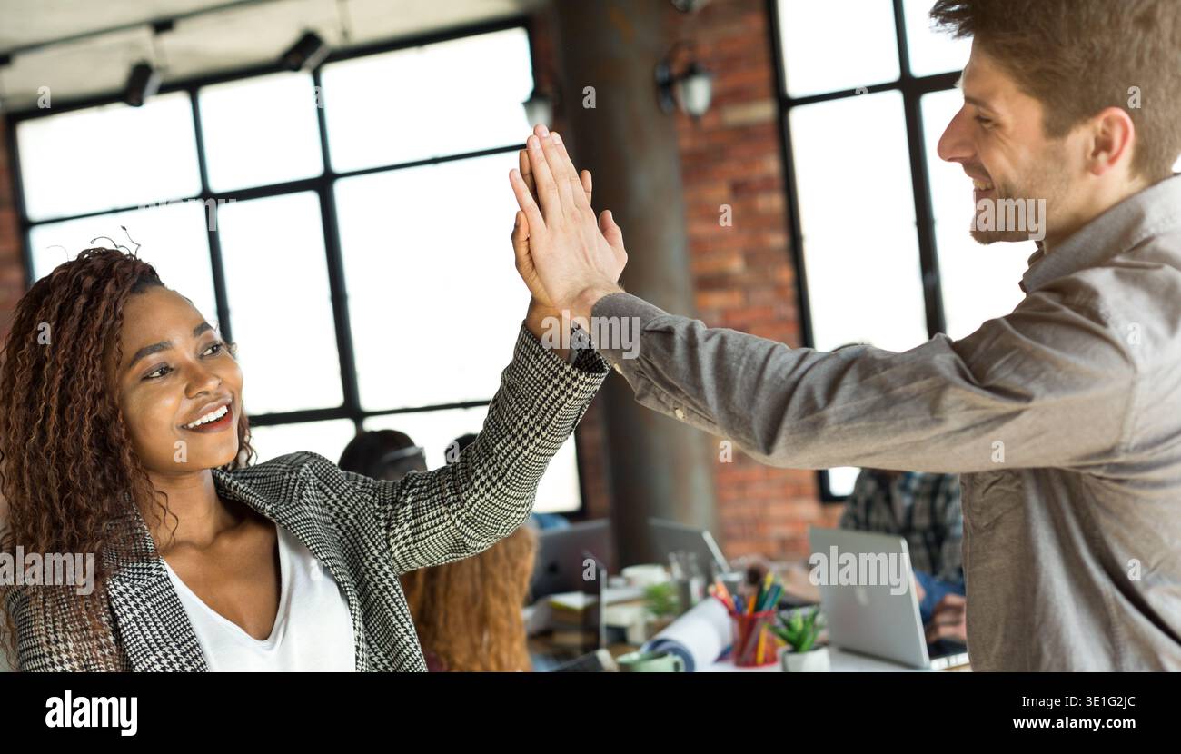Diverse colleagues giving high five at office meeting Stock Photo