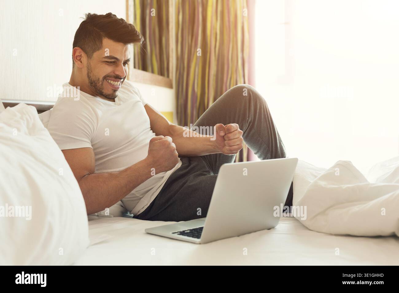 Businessman sitting on bed and using laptop Stock Photo