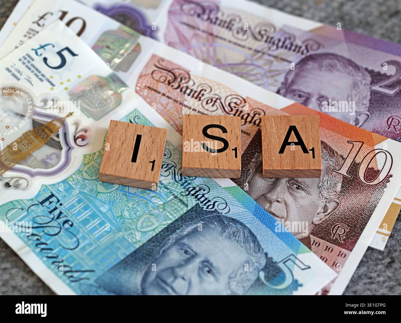 Scrabble letter tiles spelling ISA on Bank of England King Charles III banknotes, illustrating the UK Individual Savings Account deadline in April Stock Photo