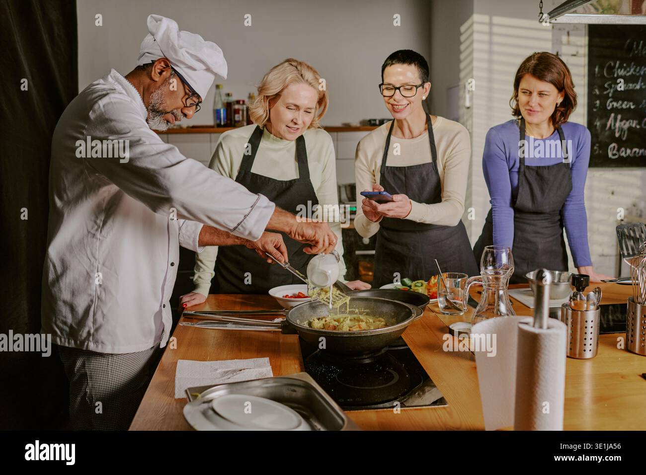 Middle Aged Man Teaching Women Cooking during Class Stock Photo