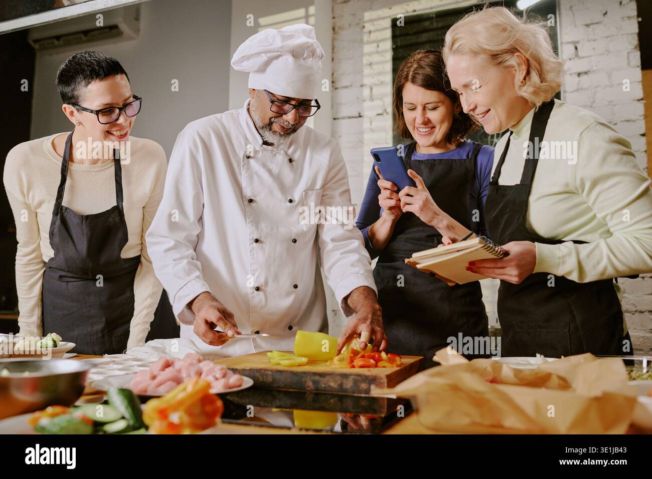 Middle Aged Man Teaching Cooking Class to Diverse Women Stock Photo
