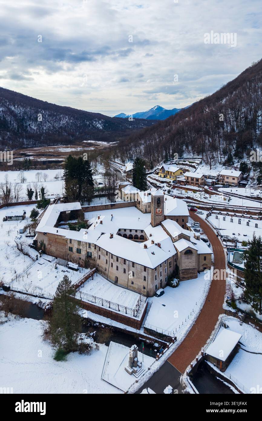 Aerial view of the ancient Badia di San Gemolo in Ganna on a winter day after a snowfall. Valganna, Varese district, Lombardy, Italy. Stock Photo