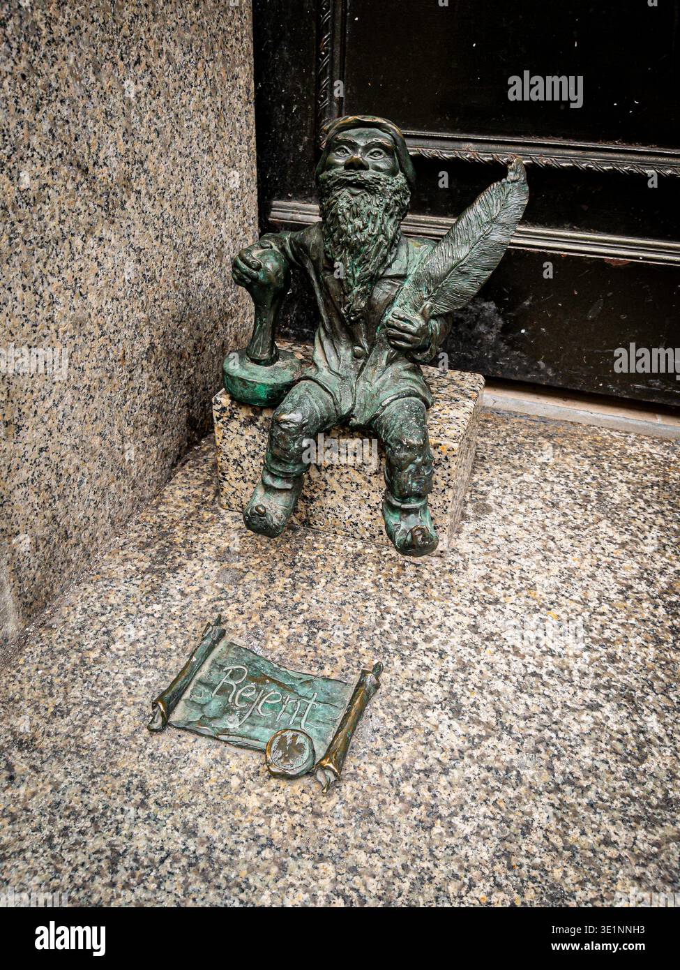 Bronze dwarf sculpture holding a quill pen beside a bronze scroll, one of the Wrocław Dwarfs (Krasnale) public art installations, Wrocław, Poland Stock Photo
