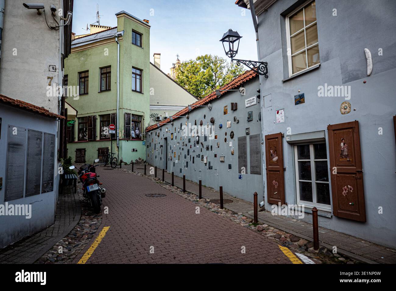 Cobbled street with lamp post and wall covered in artworks in Užupis artists' quarter, Vilnius, Lithuania Stock Photo