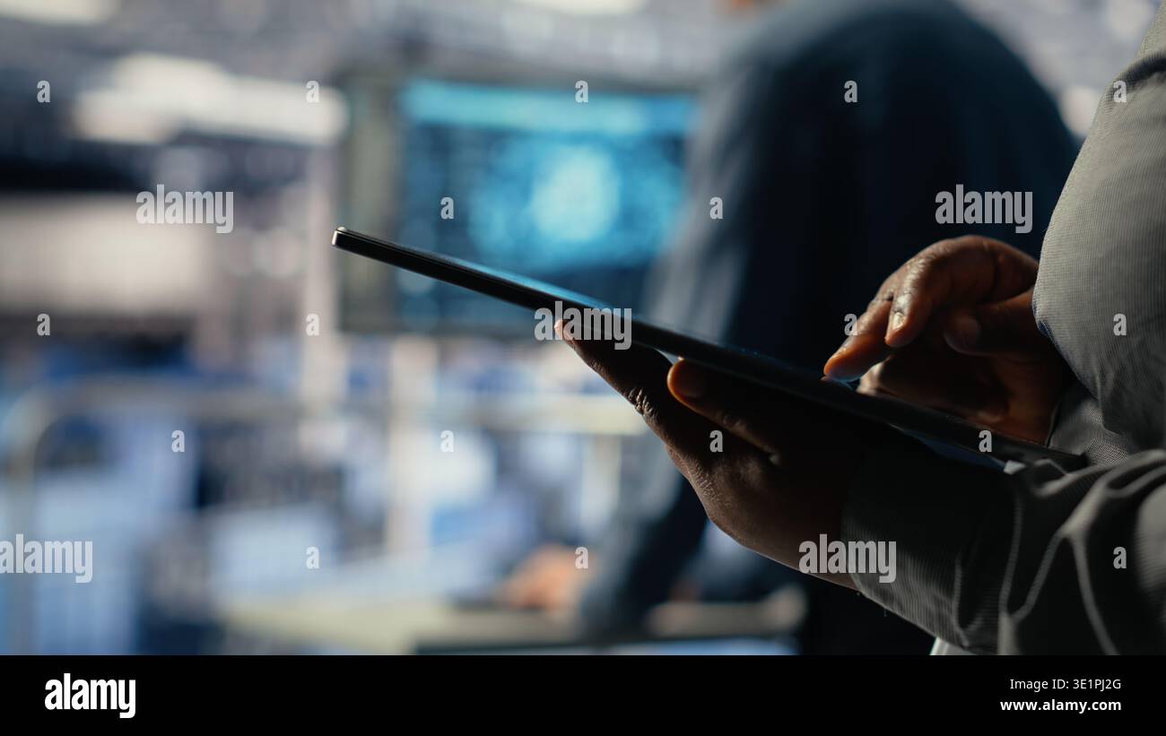 Data center programmers check AI dashboard using tablet, doing systems review. Server hub coworkers test artificial intelligence tools on device to ensure reliable performance, camera B Stock Photo